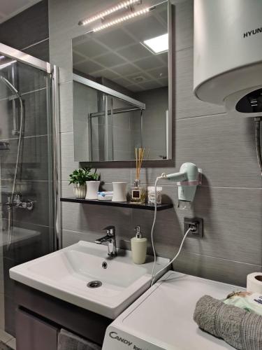 a bathroom with a sink and a shower and a mirror at 18th & 16h Floor Secure Luxury Condos With Pool & Fitness Included In Price in Skopje