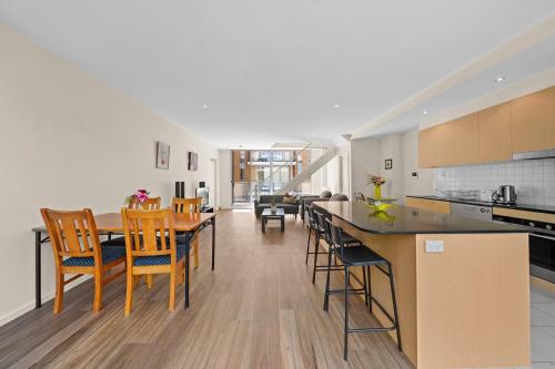 キャンベラにあるSpacious Apartment with Gym & Pool Accessのテーブルと椅子のあるキッチンとダイニングルーム