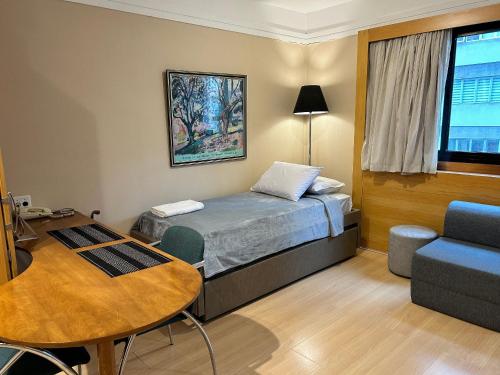 um pequeno quarto com uma cama, uma mesa e uma cadeira em TOP quarto Stay Inn hotel 3 min Av Paulista em São Paulo