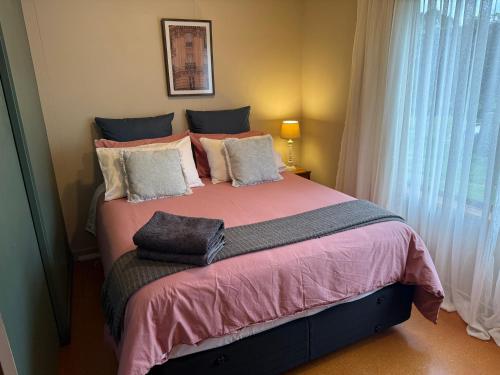 a bedroom with a large bed with pink sheets and pillows at Country Cutie-Pie, close to town in Hastings
