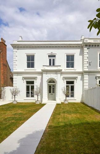 a white house with a green lawn in front of it at Double-Bed Bedroom, Living Room and Kitchenette, private Bathroom and Utility Room available at Willow House, Shepperton in Shepperton