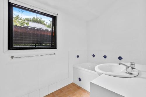 レインボー・ビーチにある43 Satinwood Drive Rainbow Shoresの洗面台と窓のある白いバスルーム