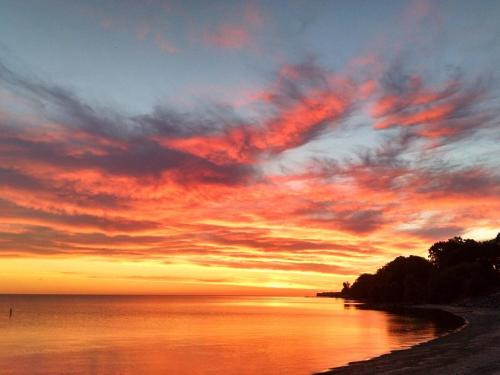 a sunset on the beach with a cloudy sky at Firefly Beach in Huron