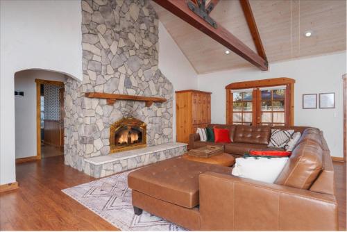a living room with a couch and a stone fireplace at Cedar Creek Lodge with POOL/hot tub/sleeps 24! in Oakhurst
