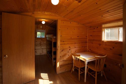 Plymouth Rock Camping Resort One-Bedroom Cabin 6 في Elkhart Lake: كابينة خشبية فيها طاولة وكراسي