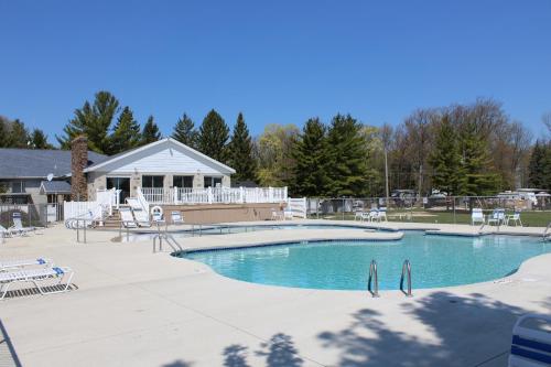 a large swimming pool with chairs and a house at Plymouth Rock Camping Resort One-Bedroom Cabin 6 in Elkhart Lake