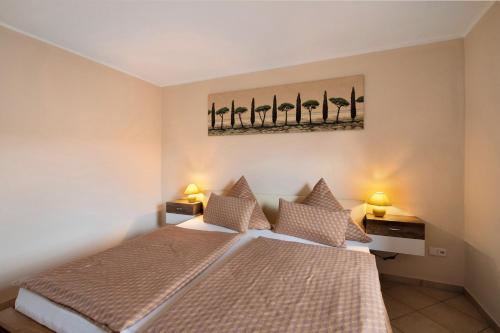 a bedroom with a bed with two lamps and a painting on the wall at Ferienwohnung Fred in Warenshof