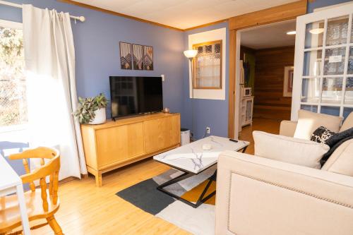 a living room with a couch and a tv at 3 Bedroom Gardenside Downtown Home in Whitehorse