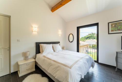 a white bedroom with a bed and a large window at L'ecrin du Ventoux in Crillon-le-Brave