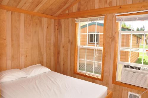 a bedroom with a bed and two windows at Plymouth Rock Camping Resort Rustic Cabin in Elkhart Lake