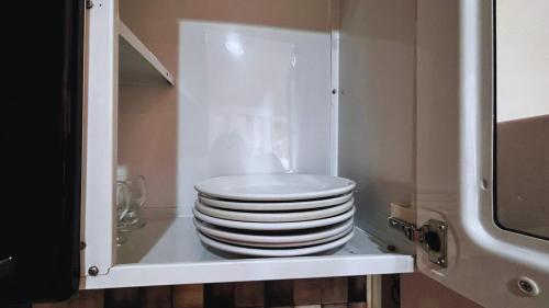 ein Stapel Teller in einem Schrank in der Unterkunft Apartamento no Centro de Gramado, 700 m da Rua Coberta in Gramado