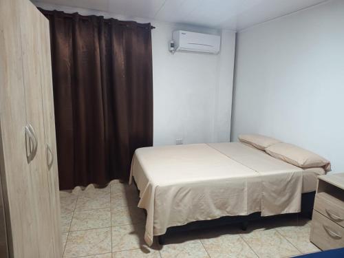 a bedroom with a bed and a brown curtain at Departamentos Don Julio in Guaraní