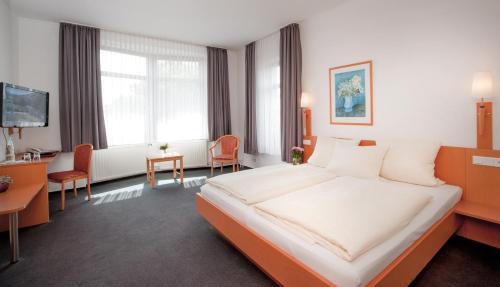ein Hotelzimmer mit einem großen Bett und einem Schreibtisch in der Unterkunft Hotel Hollmann in Halle Westfalen