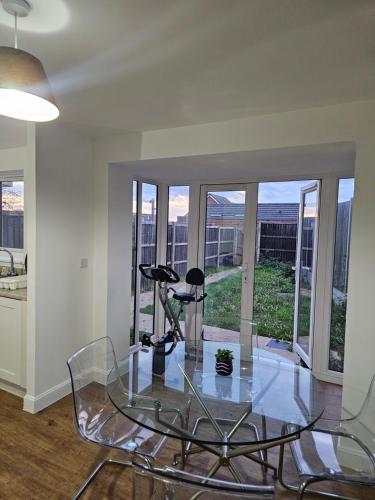 a glass table and chairs in a room with windows at Cosy Ensuite Doubleroom with Private Toilet and Bathroom in central Dartford in Dartford