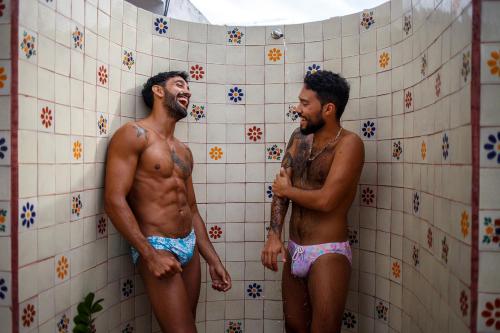 two men are standing in a bathroom stall at La Iguana Vallarta LGBT ADULTS ONLY - Romantic Zone - Party Clubbing Street in Puerto Vallarta