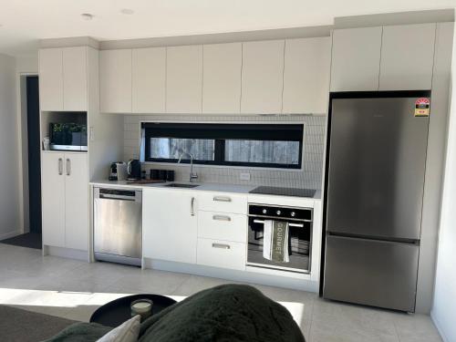 a kitchen with white cabinets and a stainless steel refrigerator at The Park Premium 2 Bedroom Apartment in Christchurch