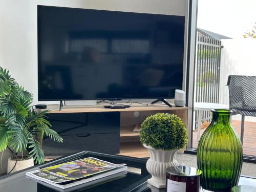 a living room with a tv and a vase on a table at The Park Premium 2 Bedroom Apartment in Christchurch