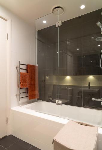 a bathroom with a tub and a glass shower at Stadium Retreat in Sydney