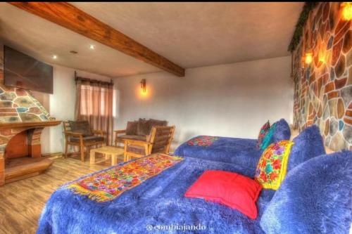 a bedroom with a large blue bed with pillows at Hotel Posada El Camino in Chignahuapan