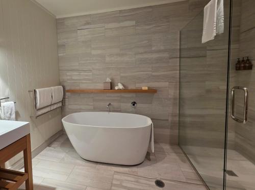 a bathroom with a tub and a glass shower at Treetops Lodge & Estate in Rotorua