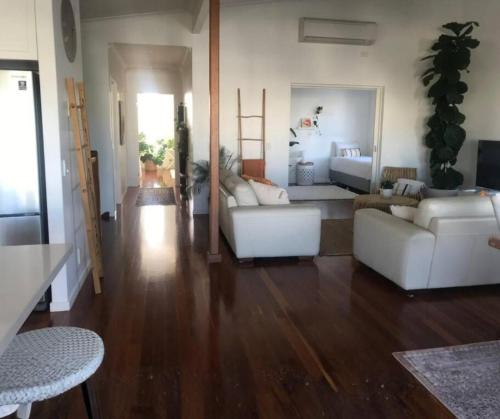 a living room with white furniture and a wooden floor at Beach Retreat Casuarina Near Osteria Weddings in Casuarina