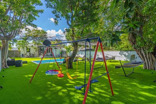 a playground with a swing set in a yard at CasaMia Only 10 min to Wynwood with New Pool, Bikes, Parking and Privacy in Miami