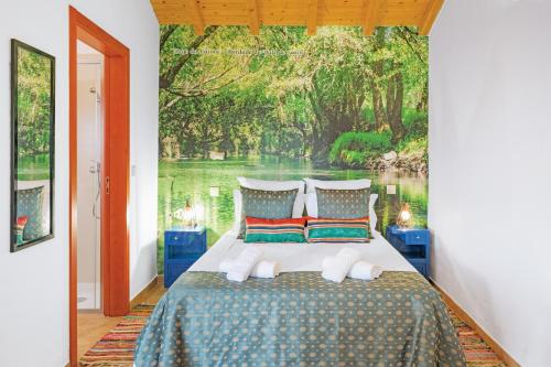 a bedroom with a bed with a painting on the wall at Herdade Vale de Gaios in Odemira