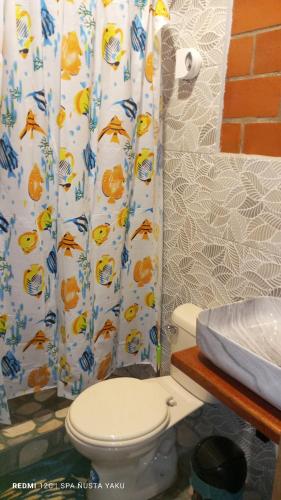 a bathroom with a toilet and a shower curtain at Wasi ñusta Yaku in Archidona