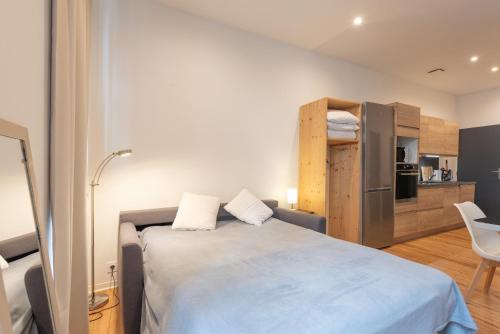 a bedroom with a large bed and a kitchen at Studio Neuf in Bagnères-de-Bigorre