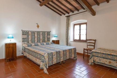 a bedroom with a bed and a chair and a window at Santa Lina - Gelsomino in Pomarance