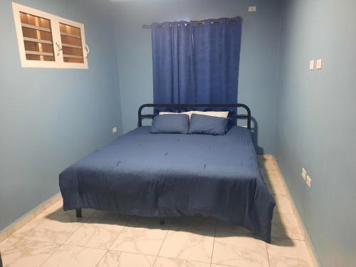 a blue bedroom with a bed with blue sheets and a window at Nos Soño in Upper Prince's Quarter