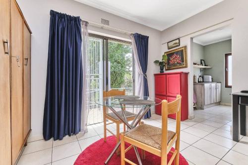 eine Küche mit einem Glastisch und Stühlen im Zimmer in der Unterkunft The Cozy 1 bedroom apartment in Roodepoort