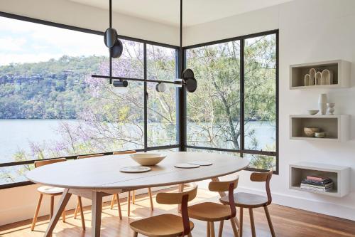 a dining room with a table and chairs and a large window at Calabash Bay Lodge in Berrilee