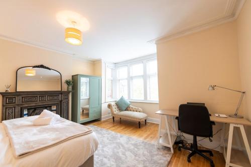 ein Schlafzimmer mit einem Bett, einem Schreibtisch und einem Stuhl in der Unterkunft The Shakespeare -5Bed 3Bath in Ealing