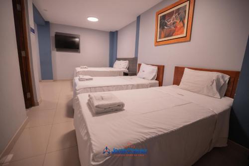 two twin beds in a room with a tv at Hotel JORGE CHAVEZ in Trujillo