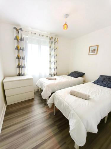 three beds in a room with white walls and wood floors at Le Clos de Valletot in Valletot