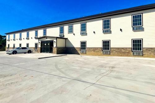 a large white building with a car parked in front of it at Efficiency de luxe hotel in Sulphur