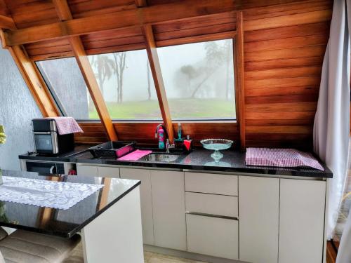 a kitchen with a counter with a sink and a window at Cabanas Laurita BG in Bento Gonçalves