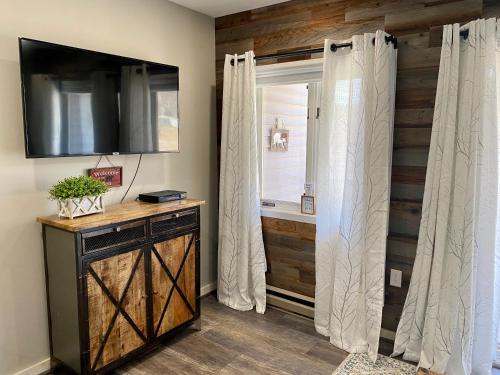 a room with a window with a curtain and a television at Loon Mountain Retreat with Pool and Hot Tub in Lincoln
