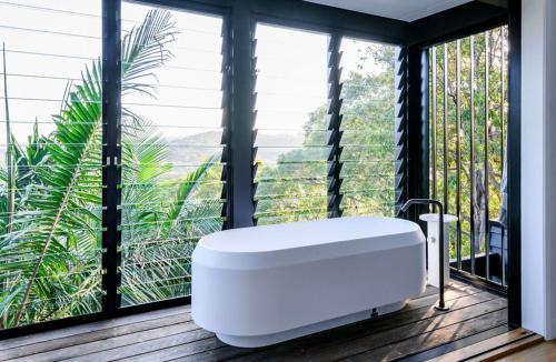 a bath tub in a room with large windows at Crane Lodge in Whale Beach
