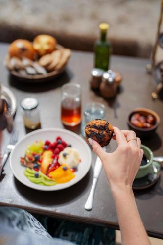 a person holding a piece of food in front of a plate of food at Nomad's Land Marrakech in El Karia