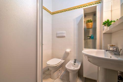 a white bathroom with a toilet and a sink at Villa Meridiana in Isola Rossa