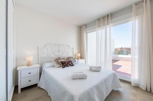 アルメリアにあるÁtico nuevo con piscinaのベッドと大きな窓のある白い寝室