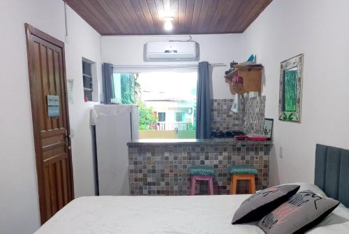 a kitchen with a bed and a refrigerator in a room at Flat Lua Nova - Pituba I coração da vila e caminho praias in Itacaré