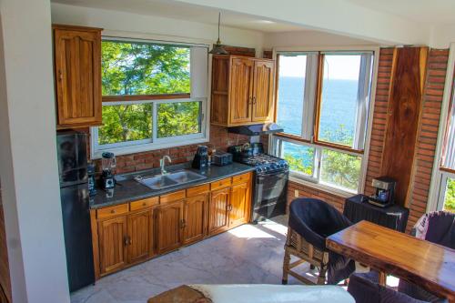 a kitchen with a sink and a table and windows at casa wow in Puerto Ángel