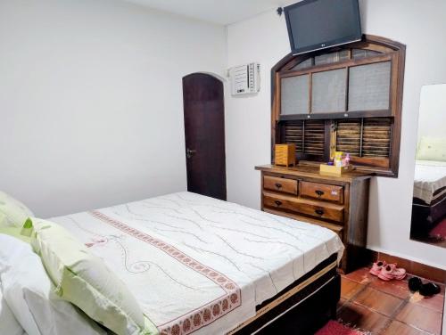 ein Schlafzimmer mit einem Bett und einer Kommode mit einem Flachbild-TV in der Unterkunft Casa Cantinho no Litoral in São Sebastião