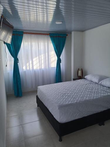 a bedroom with a bed with blue curtains and a window at La Mesa Suites - Hermosa vista in La Mesa