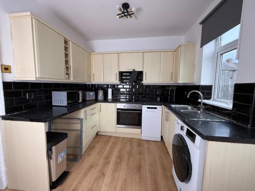 a kitchen with white appliances and black counter tops at Spacious 3 Bed House Perfect for Contractors & Families with free Wi-fi and Parking in Rawmarsh