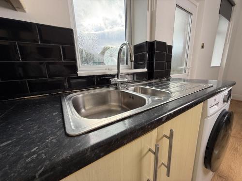 a kitchen with a stainless steel sink and a window at Spacious 3 Bedroom With Garden and Free Parking in Rawmarsh