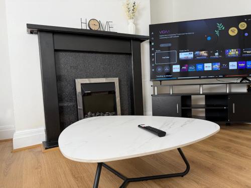 a remote control sitting on a white table in front of a fireplace at Spacious 3 Bed House Perfect for Contractors & Families with free Wi-fi and Parking in Rawmarsh